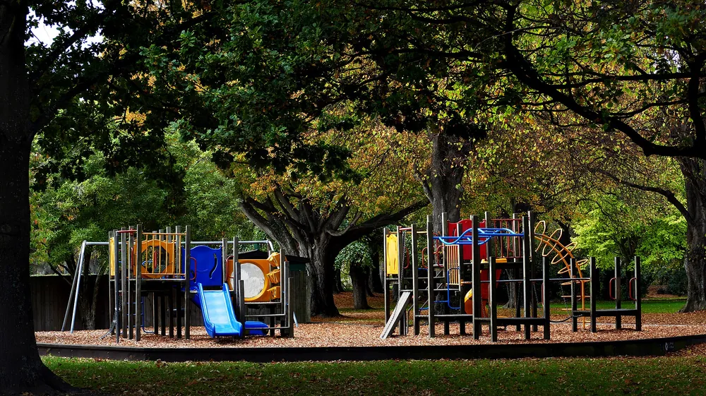 An empty children&rsquo;s playground under trees